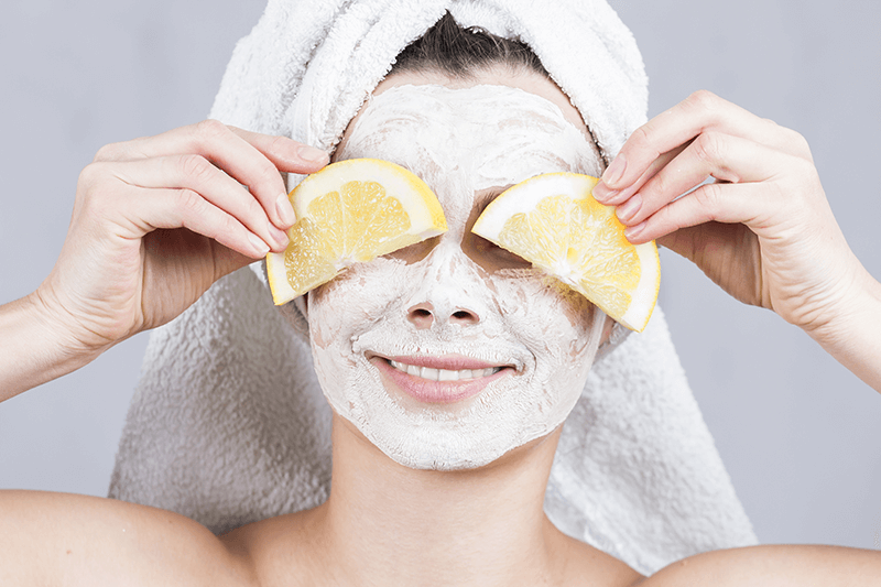 Woman in face mask holding lemon slices.